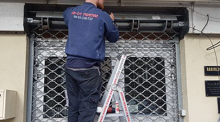 Installation d'une grille à mailles par un technicien de l'entreprise Sud Est Fermeture